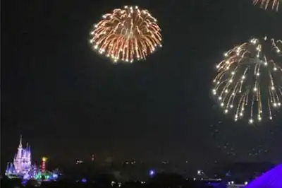Nighttime helicopter view of fireworks over Orlando theme parks with colorful explosions lighting the skyline